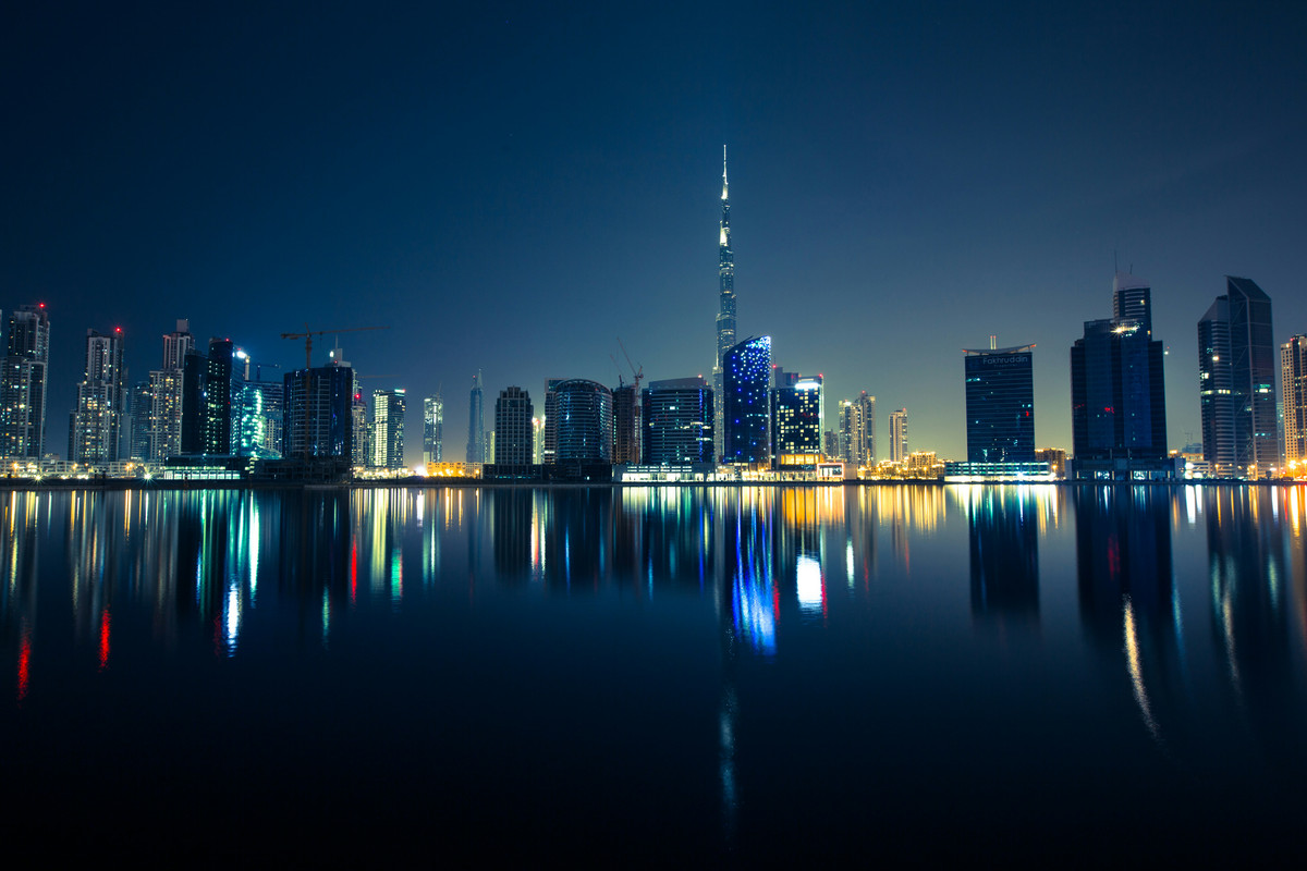 Dubai skyline at night with the water reflecting the skyline and Burj Khalifa in the background