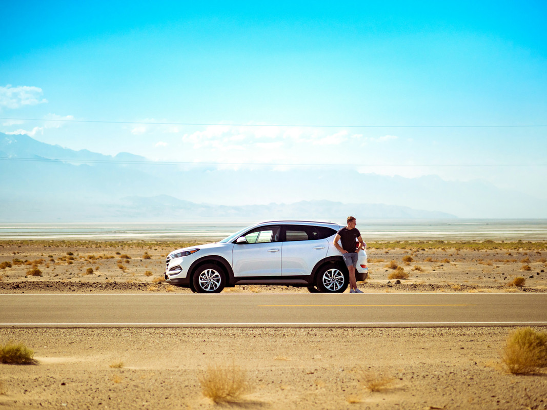 Man standing by his car in the desert